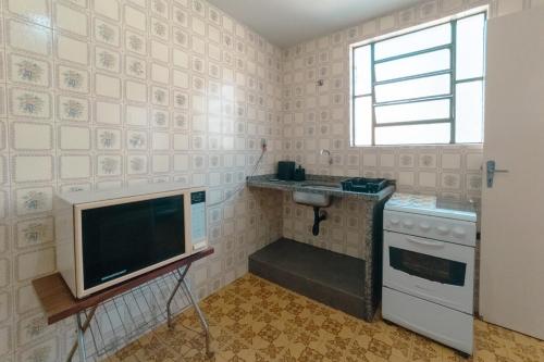 a small kitchen with a television and a sink at Central, Barato e Espaçoso in Maringá