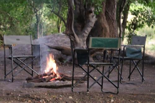 a camp fire with two chairs and a table at Khwai Game Lodge and Campsite in Khwai
