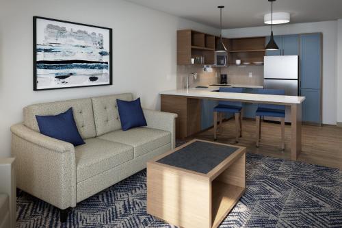 a living room with a couch and a kitchen at Candlewood Suites Chatham South by IHG in Chatham