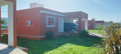 ein rotes Haus mit einem Van davor geparkt in der Unterkunft Cabañas Hawaii in Bialet Massé