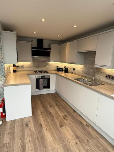 eine Küche mit weißen Schränken und einem Holzboden in der Unterkunft Luxury townhouse in Stirling in Stirling