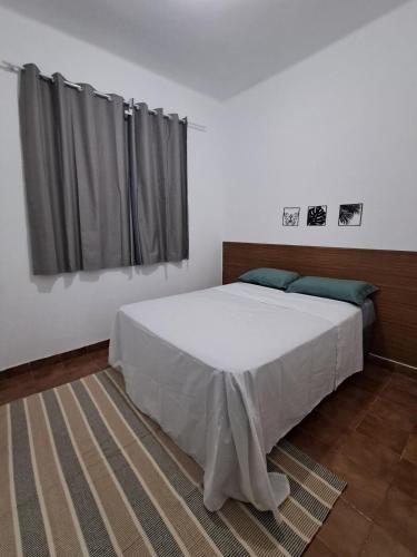 a bedroom with a large white bed with a window at Great central apartment in Duque de Caxias