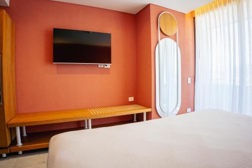 a bedroom with orange walls and a tv on the wall at Zapadilly Tree Hotel in San Andrés