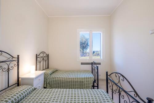 a bedroom with two beds and a window at Villa Corbezzolo in Galatone
