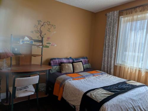a bedroom with a bed and a desk and a window at citadel cozy quilt private bedroom in Calgary