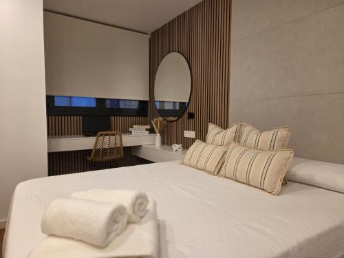 a bedroom with a large white bed with a mirror at Solsuites in Almería