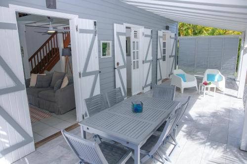 een terras met een tafel, stoelen en een bank bij La Petite Villa Guadeloupe in Sainte-Anne
