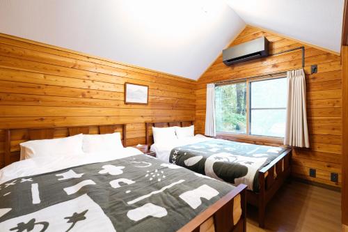 two beds in a room with wooden walls at KAGUYA Karuizawa - 輝屋 in Naganohara
