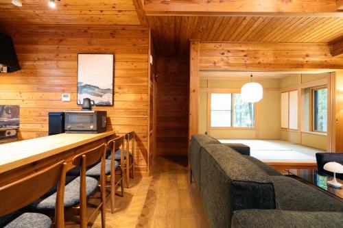 a living room with wooden walls and chairs and a bar at KAGUYA Karuizawa - 輝屋 in Naganohara