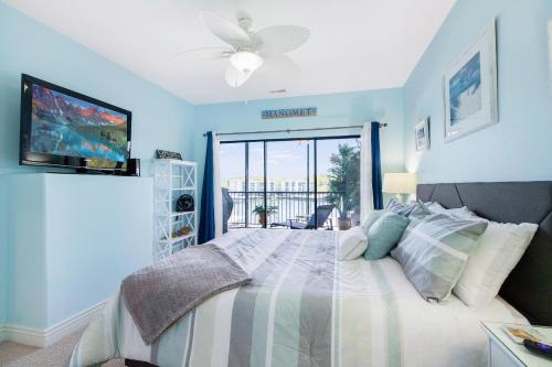 ein Schlafzimmer mit einem Bett mit blauen Wänden und einem Fenster in der Unterkunft Amazing Main Channel Views with Screened Balcony in Lake Ozark