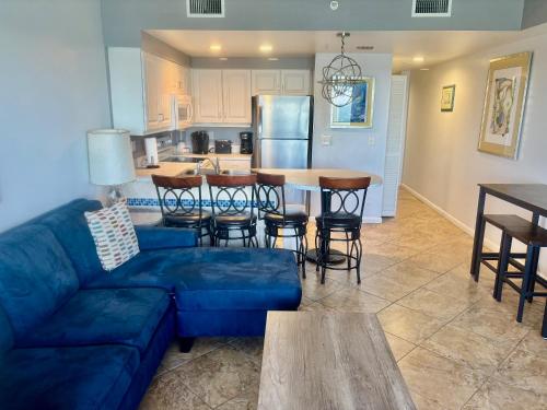 a living room with a blue couch and a kitchen at Ocean Walk Resort - Remarkable Ocean Front View in Daytona Beach
