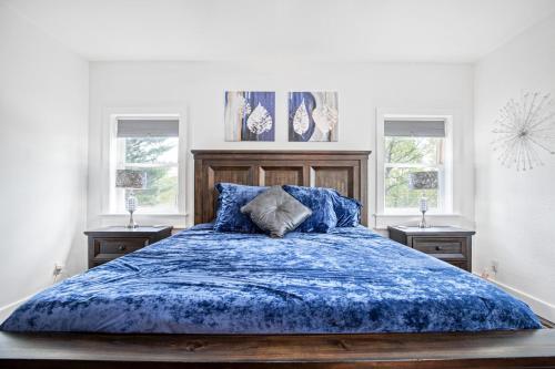 ein Schlafzimmer mit einem blauen Bett mit zwei Fenstern in der Unterkunft Amazing Sunset Lake Views, Huge Deck & Hot Tub! in Sunrise Beach