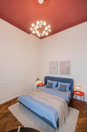 a bedroom with a blue bed and a chandelier at Central Retreat - Cozy & Charming Apartment in Arad