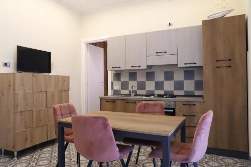 a kitchen with a wooden table and pink chairs at Domus Marina - Egeo Apartment in Mondragone