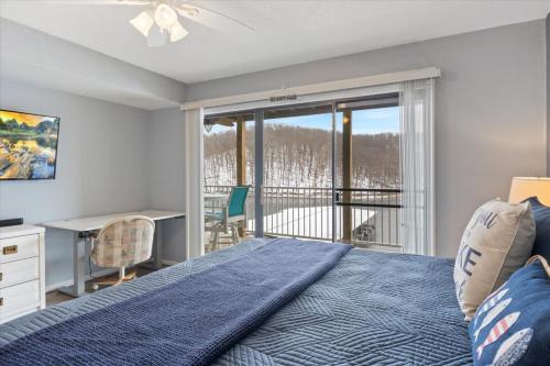 a bedroom with a bed and a desk and a balcony at Family Fun at Lake Vibin' Lazy Days Osage Beach w/ 2 Pools, Playground, Games & Calm Water in Damsel