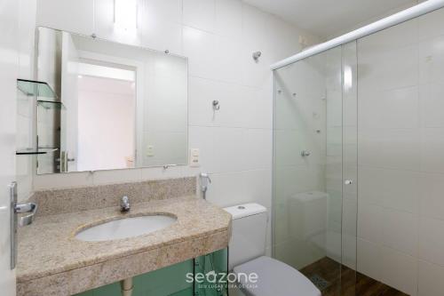 Un baño con lavabo, inodoro y espejo. en Apto c/ balcón y vista al mar en Guarapari CMD0311, en Meaípe