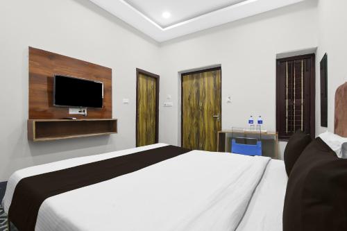 a bedroom with a white bed and a flat screen tv at Hotel O Smriti Villa in Ballygunge