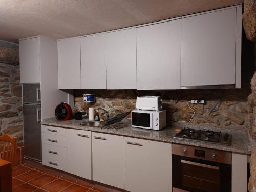 a kitchen with white cabinets and a microwave at Miranda Guest House