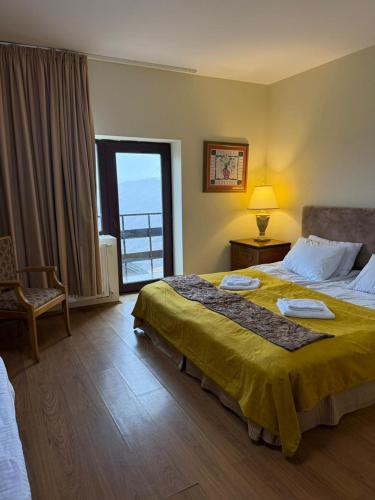 a bedroom with a large bed with a yellow blanket at Hotel Wintera Gudauri in Gudauri