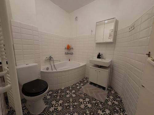 a bathroom with a tub and a toilet and a sink at Míra Apartman in Gödöllő