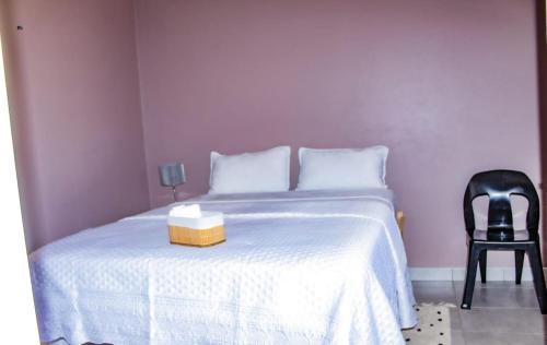 a bedroom with a white bed and a black chair at Bothoba Bed and Breakfast in Maseru