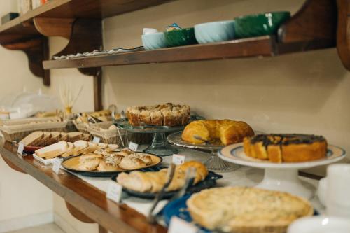 Una mesa llena de diferentes tipos de pasteles y tartas. en Pousada Florescer, en Ubatuba
