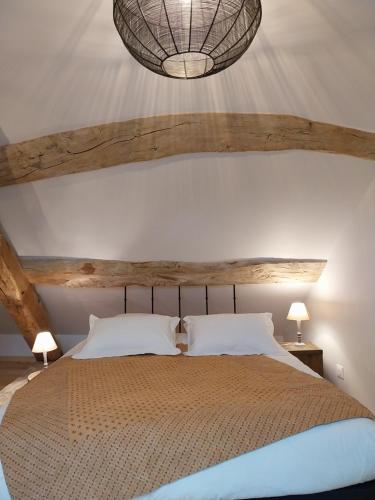 a bedroom with a large bed and a chandelier at L'Armandine in Saint-Marcel-Bel-Accueil
