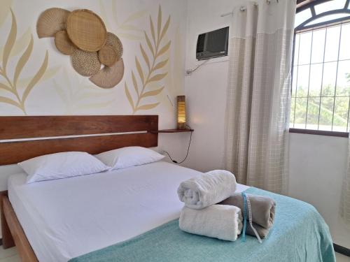 a bedroom with a bed with towels and a window at Odoyá Casa Hostel in Arraial d'Ajuda