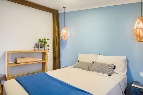 a bedroom with a bed with a blue wall at Casa Tupi - suítes no coração do Itaguá em Ubatuba in Ubatuba
