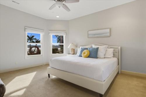 a white bedroom with a bed and two windows at Luxury Lakefront Escape w/ Heated Pool, Hot Tub & Theater in Sunrise Beach