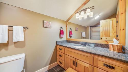 a bathroom with a sink and a toilet and a mirror at Hot Tub, Fire Pit, Awesome Loft & Amazing Views! in Buck Creek