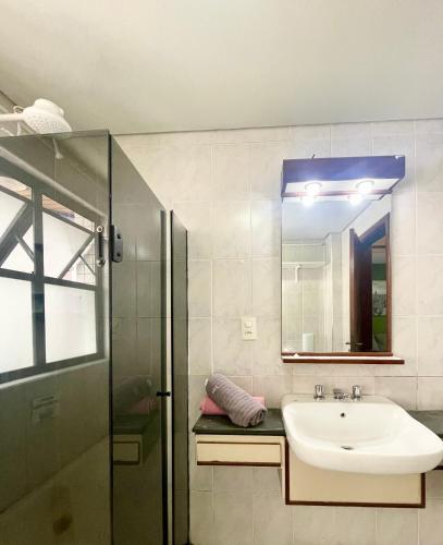 a bathroom with a sink and a glass shower at Jungle City Flat in São Vicente