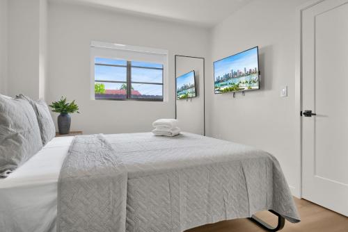 a white bedroom with a bed and two windows at Prestige Retreat by Renzzi in Miami
