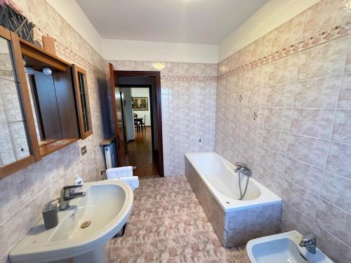 a bathroom with a tub and a sink and a bath tub at Appartamento La Coccinella in Gonàrs