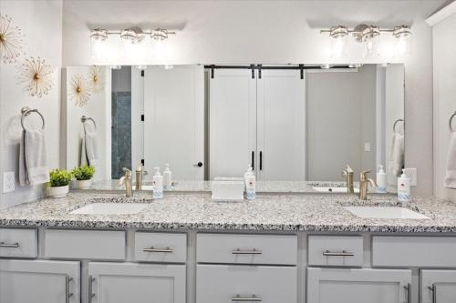 a bathroom with two sinks and a large mirror at Topsider Condo w/ Updated Design & Amazing Main Channel Views in Laguna Beach