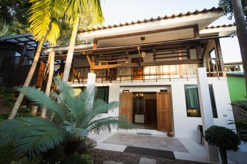a house with a front door and palm trees at Kata Tranquil Villa - SHA Plus in Karon Beach
