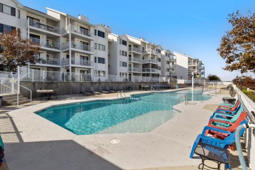 a swimming pool with blue chairs in front of a building at Pet-Friendly Condo at MM-19 w/ Boat Slip & Lake Views in Laguna Beach