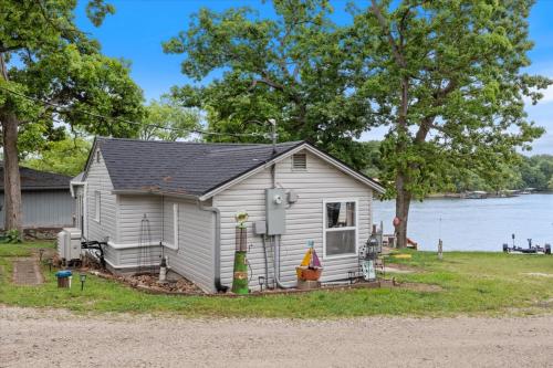 ein kleines Haus am Ufer eines Sees in der Unterkunft Lakefront Fishing Retreat w/ Dock, Hot Tub & Deck Views in Sunrise Beach