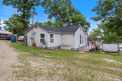 ein kleines weißes Haus mit einem Hof in der Unterkunft Lakefront Fishing Retreat w/ Dock, Hot Tub & Deck Views in Sunrise Beach