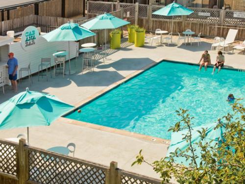 a swimming pool with blue umbrellas and people in it at Harbor Hotel Provincetown in Provincetown