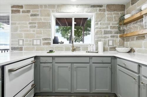 een keuken met grijze kasten en een stenen muur bij Hot Tub, Main Channel Views, Great Outdoor Spaces, Blackstone in Sunrise Beach