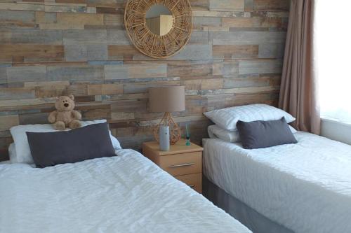 un ours en peluche assis entre deux lits dans une chambre dans l'établissement 2 Bed Chalet Sleeps 4- Parking Garden Near Beach, à Hemsby