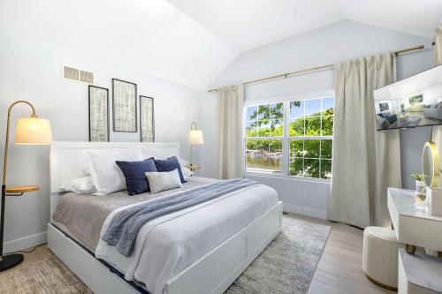 a white bedroom with a large bed and a window at Newly Remodeled w/ Dock, Boat & PWC Slips, Pool Table & Golden Tee in Damsel