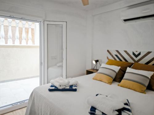 a white bedroom with towels on a bed with a window at Seaside Terraced Bungalow in La Mata in La Mata