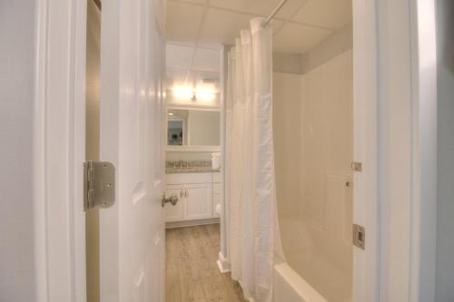 a white bathroom with a tub and a shower curtain at Verandas - 303 in Myrtle Beach