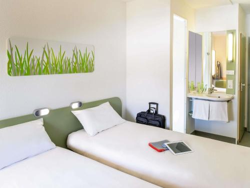 a bedroom with two beds and a sink and a mirror at Ibis budget Wien Messe in Vienna