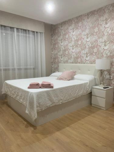 a bedroom with a bed with white sheets and pink wallpaper at Villa Lila - planta 1ª in Pontevedra