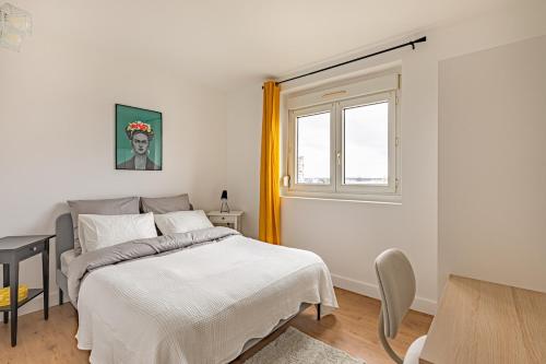a white bedroom with a bed and a window at Friendly and spacious apartment in Créteil ! in Créteil
