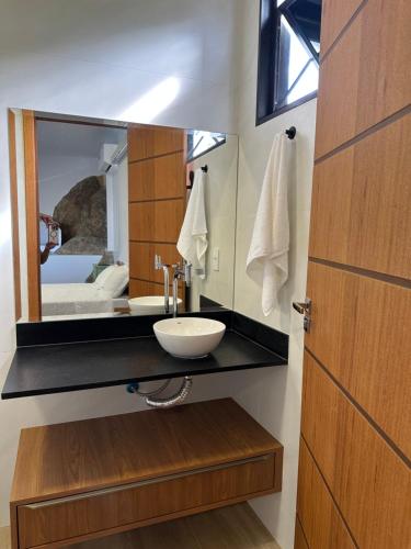 um banheiro com uma pia e um espelho em Loft MarSol em Piúma