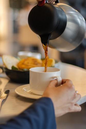 uma pessoa está despejando café em uma xícara sobre uma mesa em Hilton Bogota Corferias em Bogotá